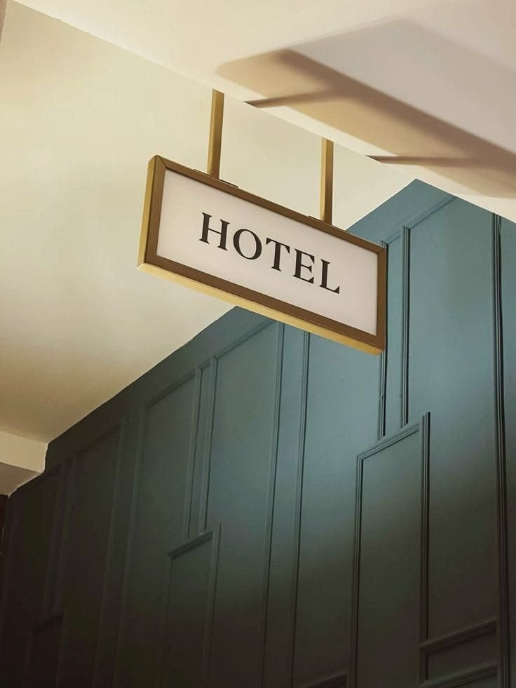 A hanging HOTEL sign against a dark green wall